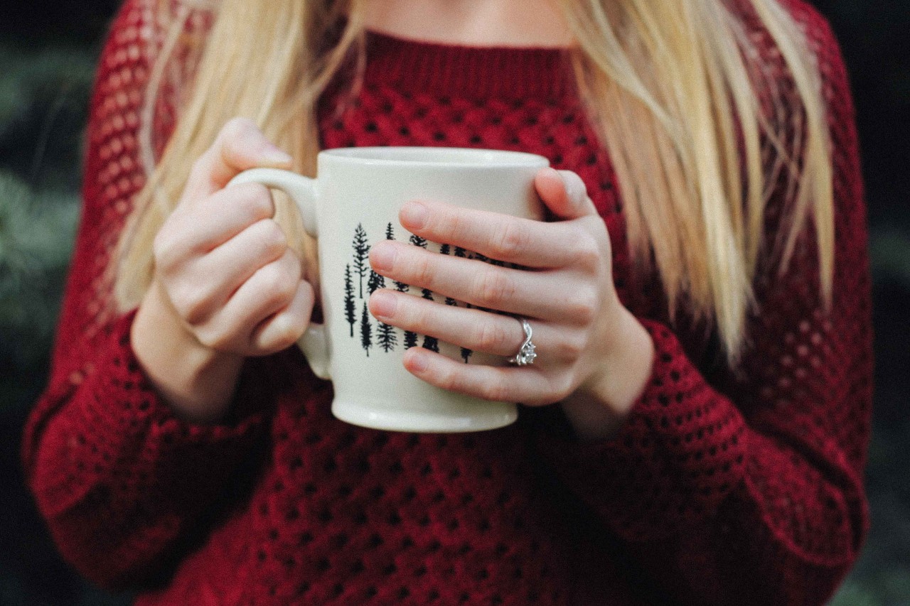 A woman sipping a mocha shows off her engagement ring at a chocolate shop