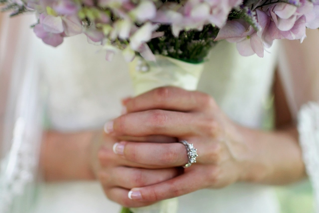 A bride wearing her engagement ring and holding a bouquet before her ceremony