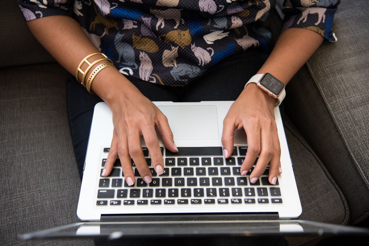 A woman wearing gold bangles plans her vacation on her laptop