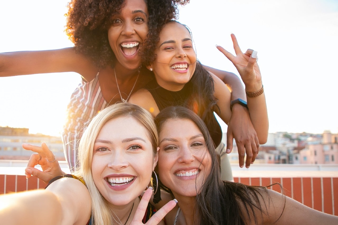 Four women on a summer vacation pose for a selfie while wearing jewelry