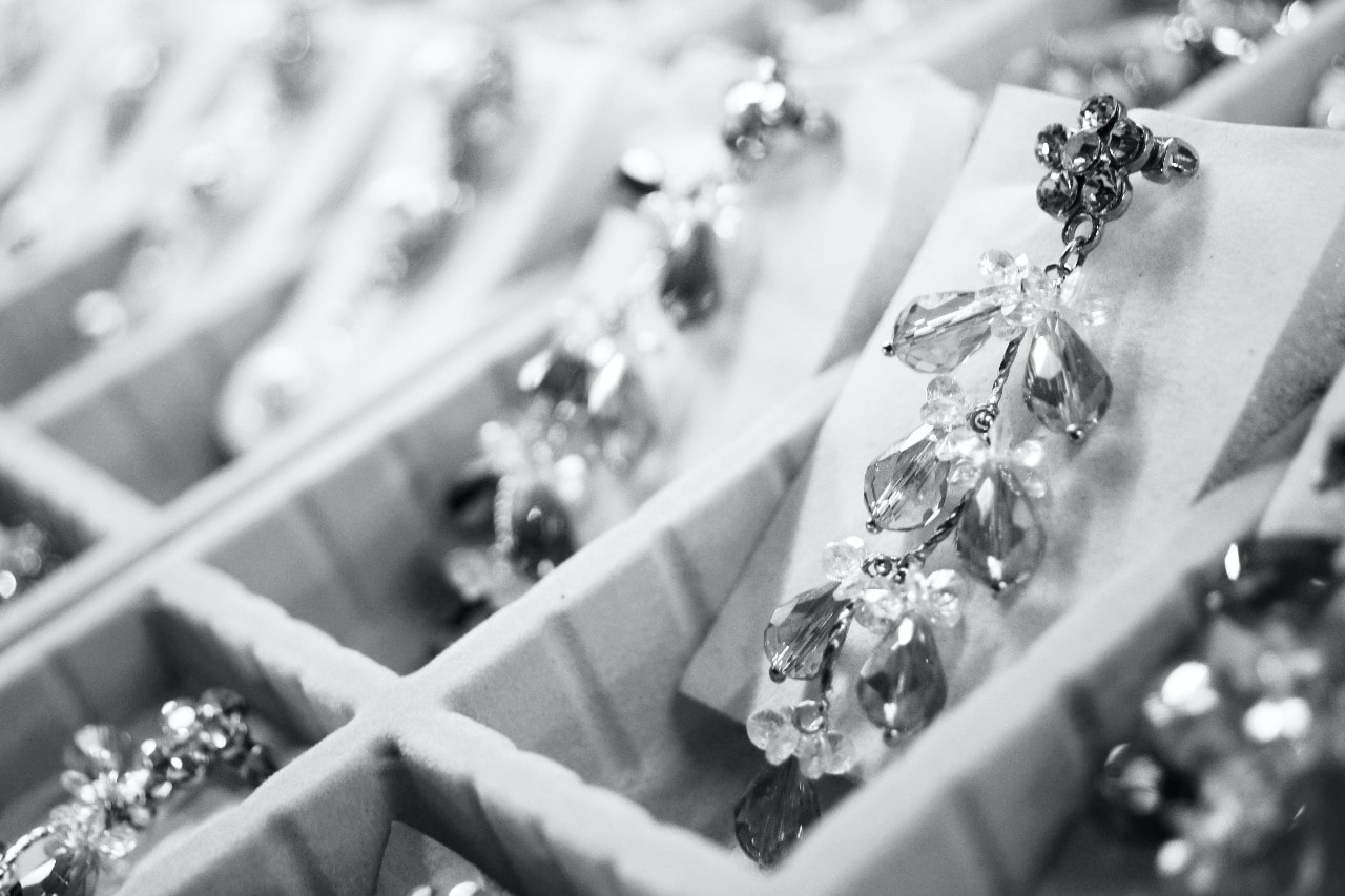 A black and white image of a jewelry case with cascading gemstone earrings.