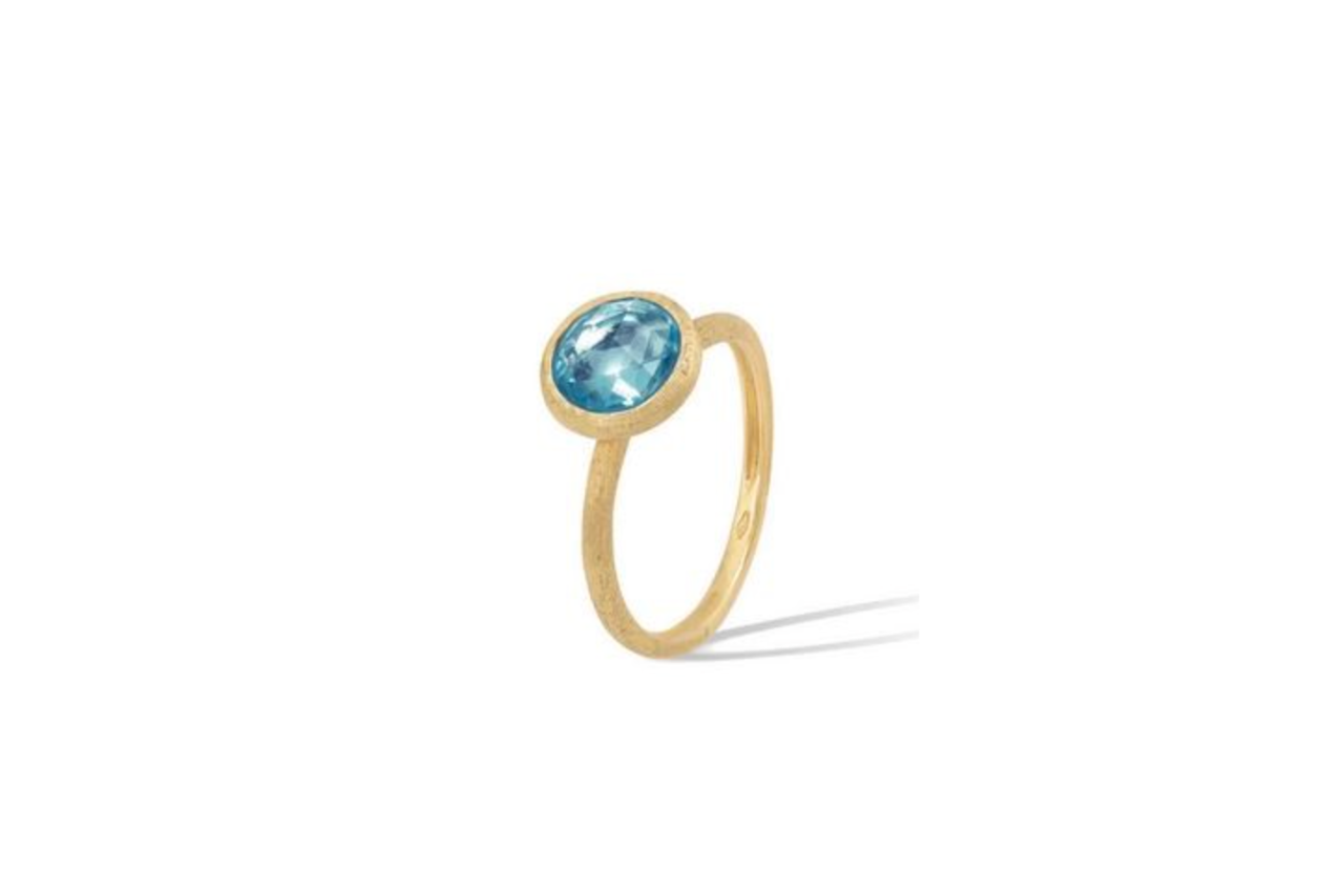 A golden ring with a bezel blue topaz center stone.