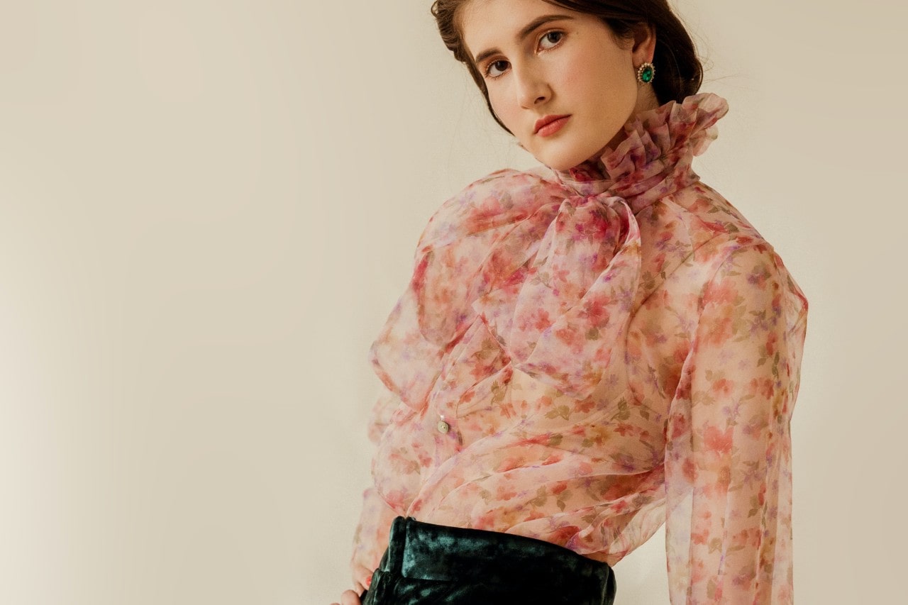 a woman in a floral top and a pair of emerald halo earrings
