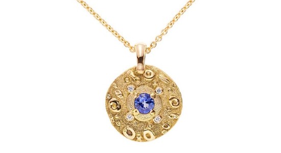 a yellow gold pendant necklace featuring a round cut sapphire center stone and diamond accents
