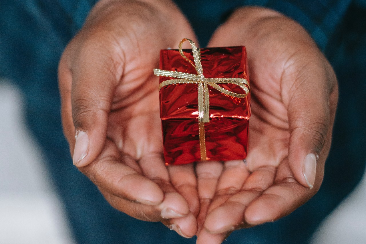 A woman holding a small, wrapped gift in her palms.