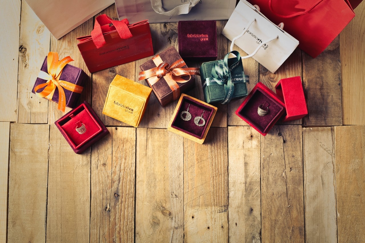 A variety of jewelry gifts lay out on a rustic wooden floor.