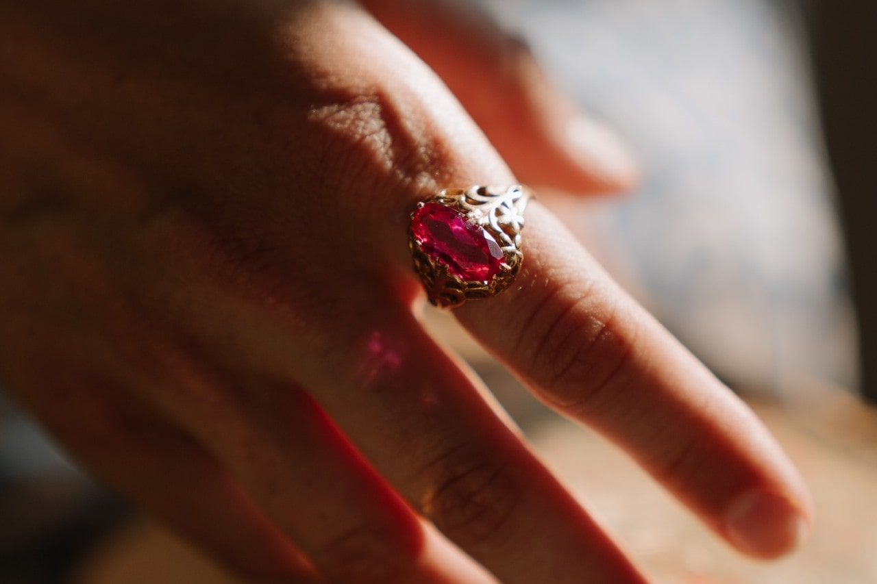close up image of a gold fashion ring featuring pink gemstone