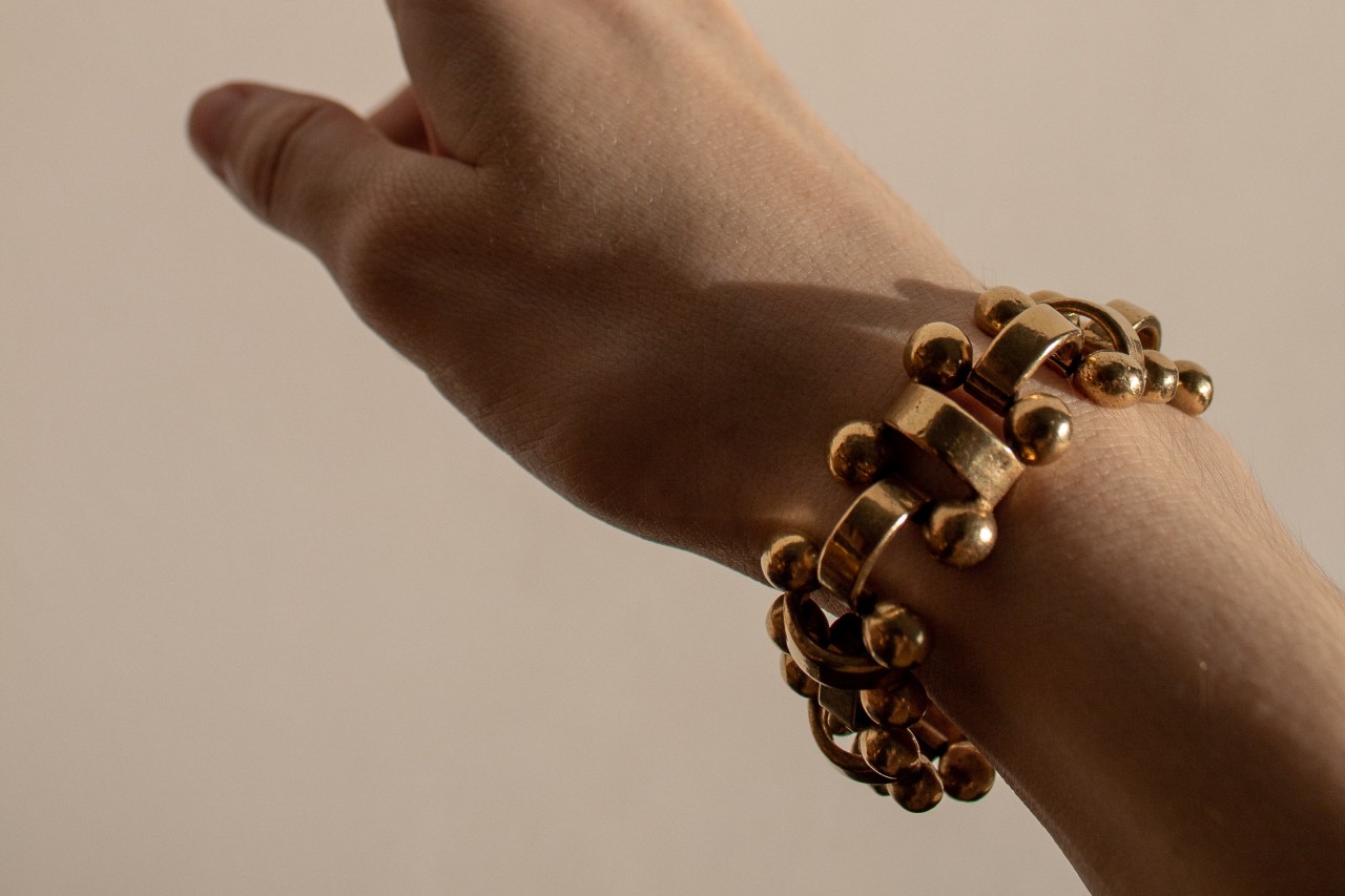 an arm extended upwards wearing a chunky gold bracelet