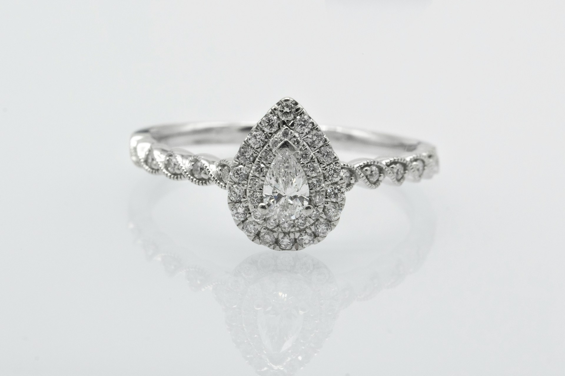 a white gold pear shape engagement ring with a double halo and side stones