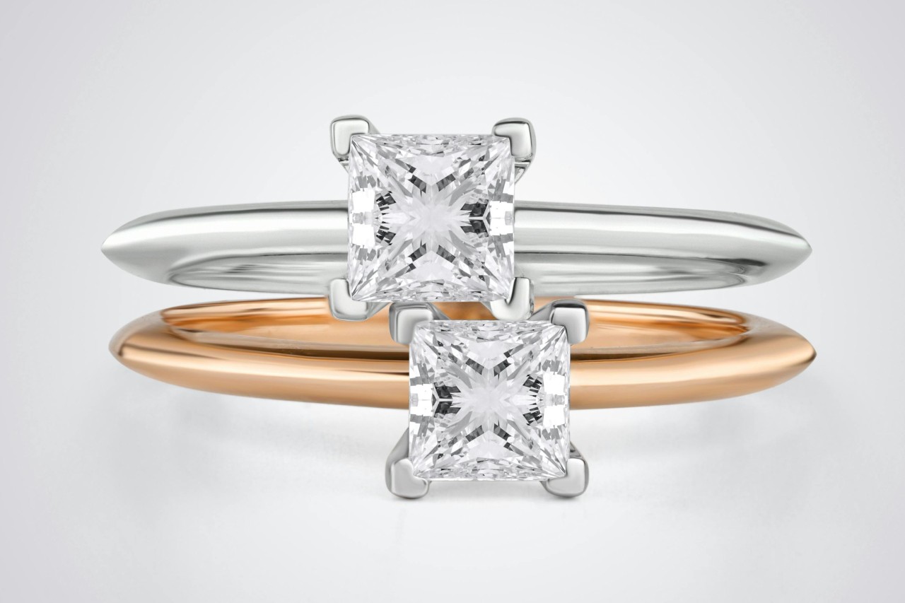 Two princess-cut engagement rings in yellow and white gold.