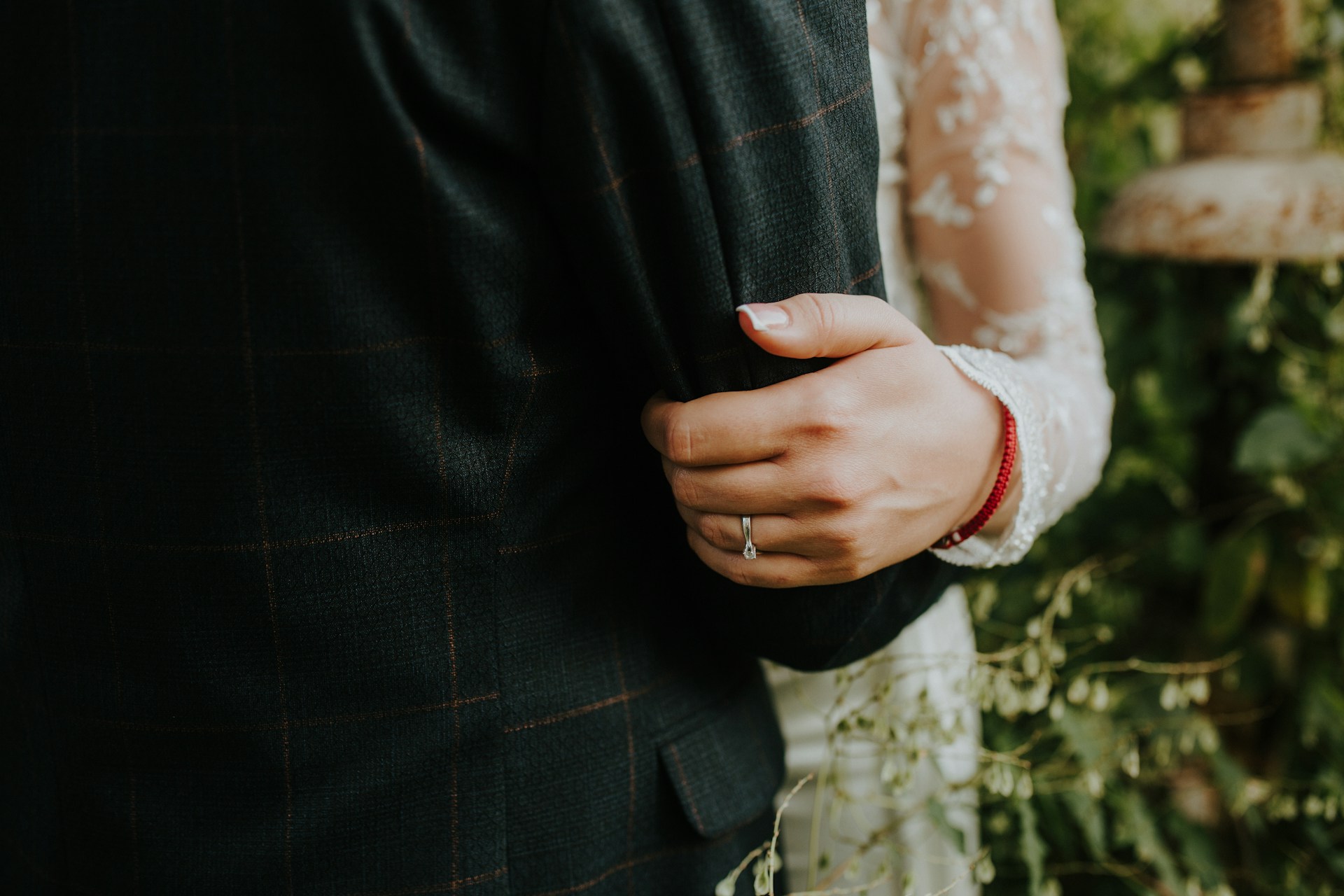 A bride holding on to the arm of her groom with a view of her diamond engagement ring A bride holding on to the arm of her groom with a view of her diamond engagement ring