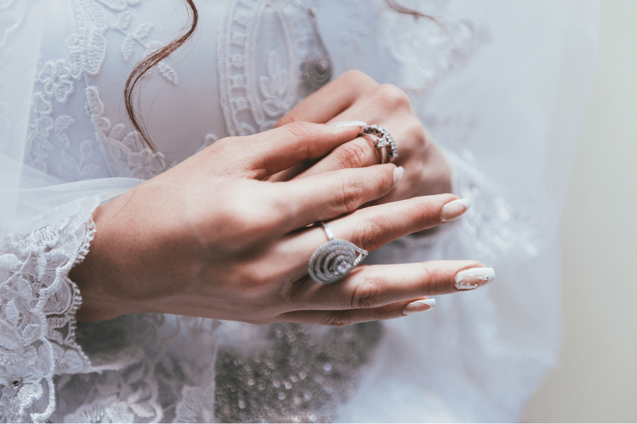 A spectacular but elegant pair of fashion rings worn by a chic lady in a lacey white shirt