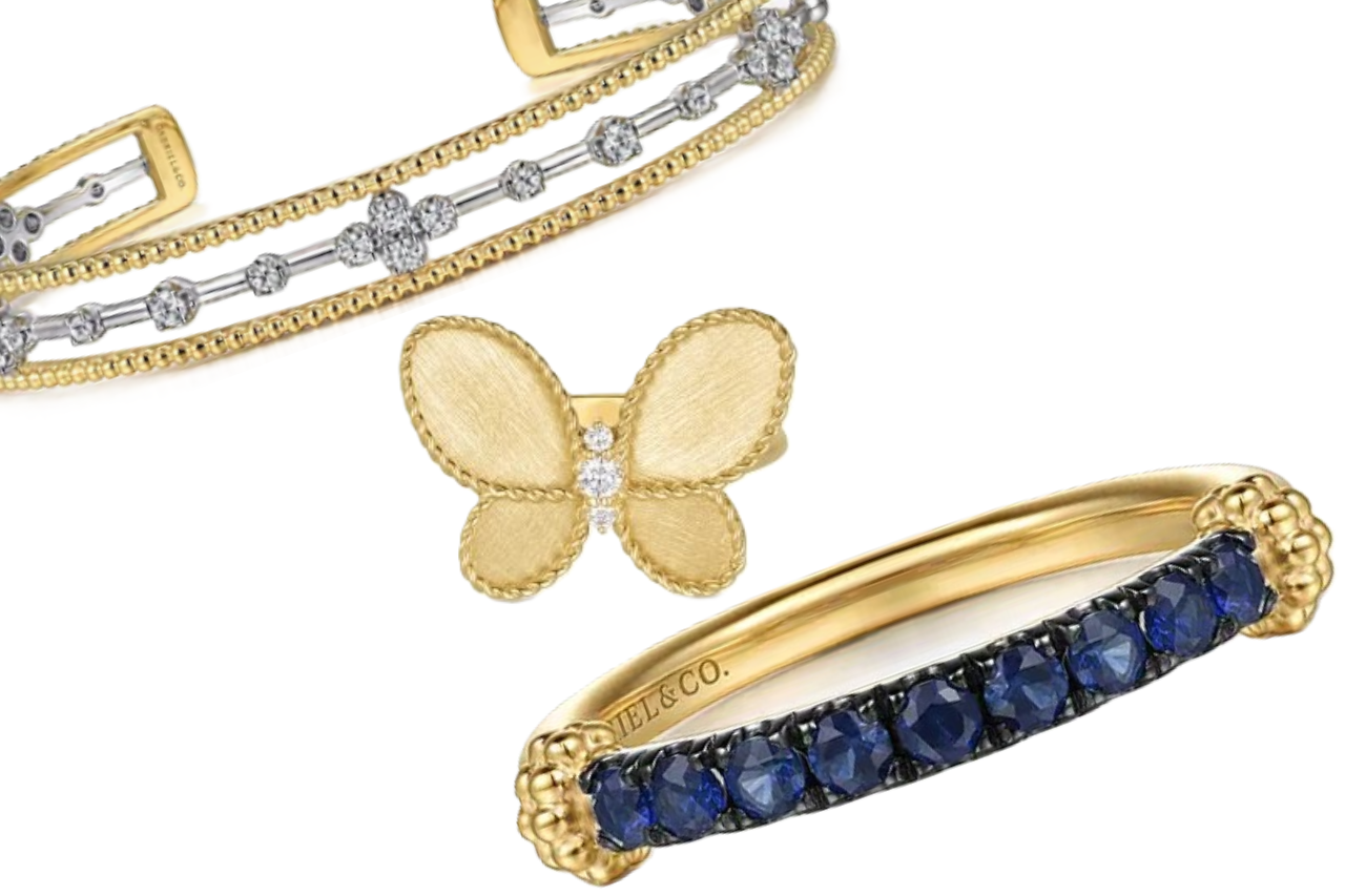 A close-up of three elegant pieces of gold jewelry, one bracelet and two fashion rings, all available at Adlers Jewelers.