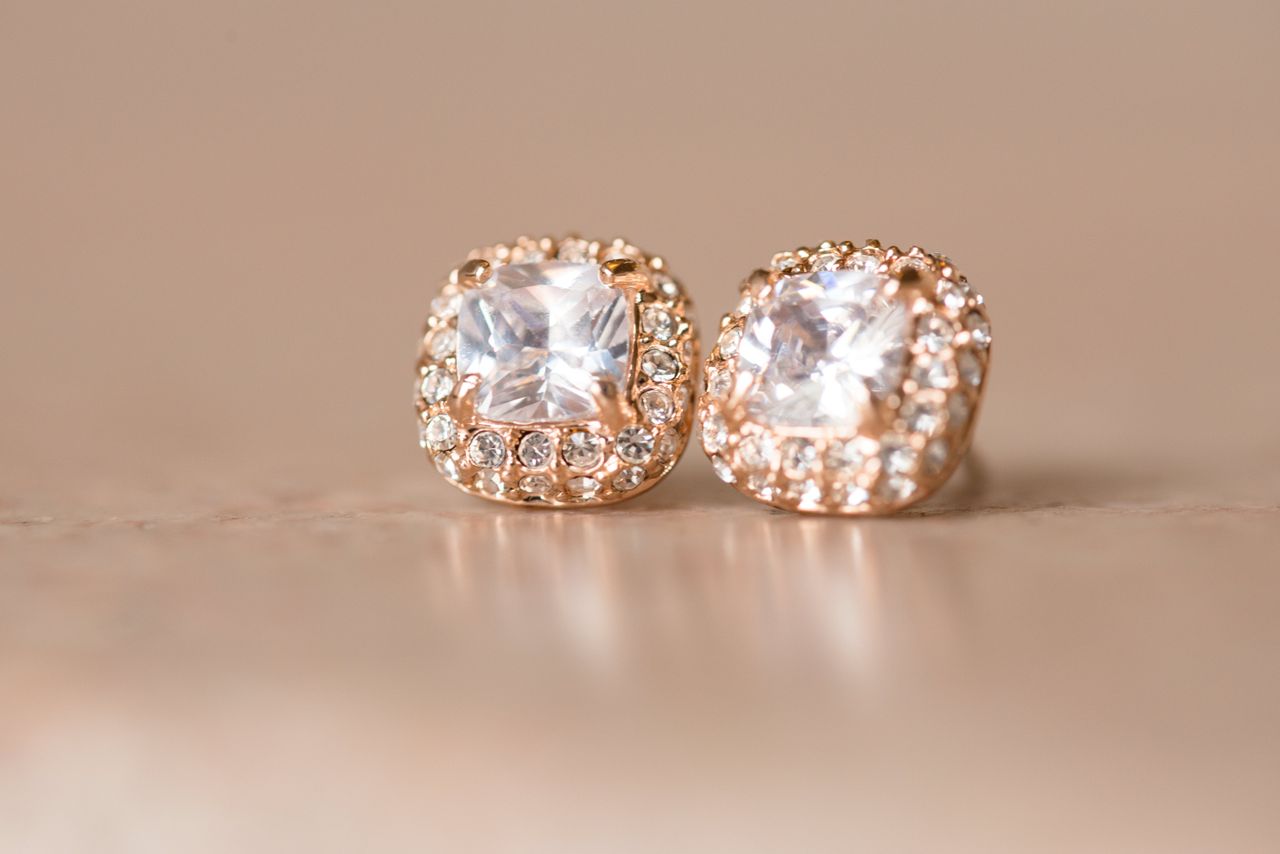 Close-up of square-cut rose gold diamond earrings with a halo of smaller diamonds.