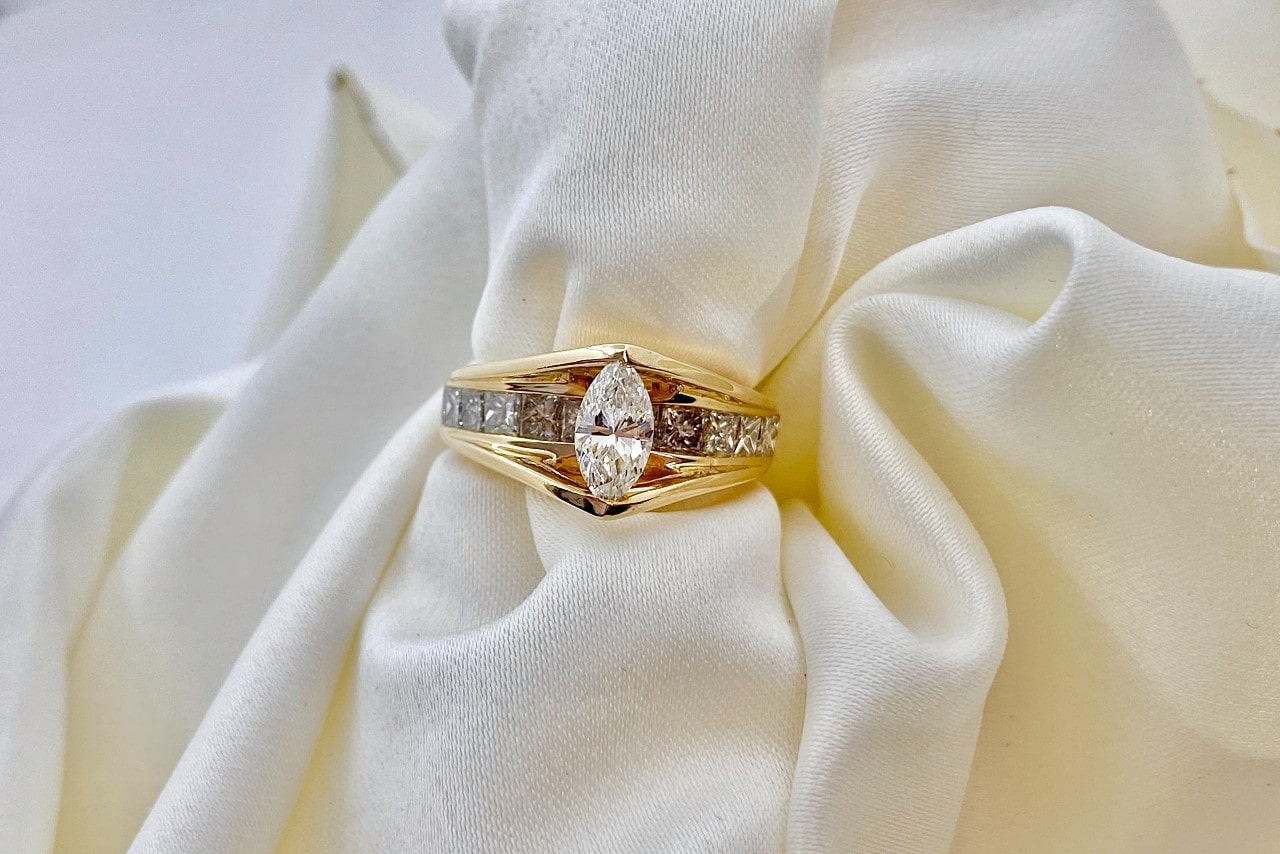 A regal yellow-gold engagement ring with a marquise cut center diamond.