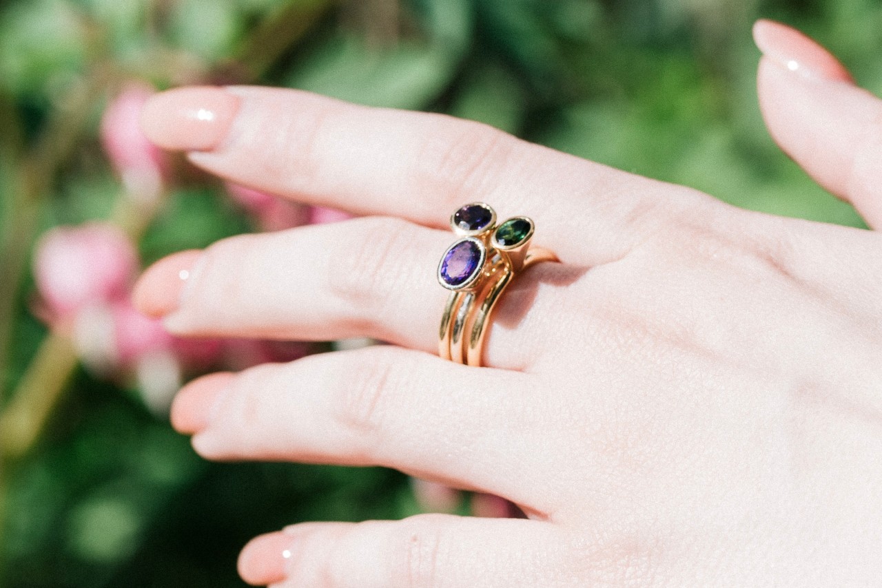 an outstretched hand wearing a stack of yellow gold gemstone fashion rings