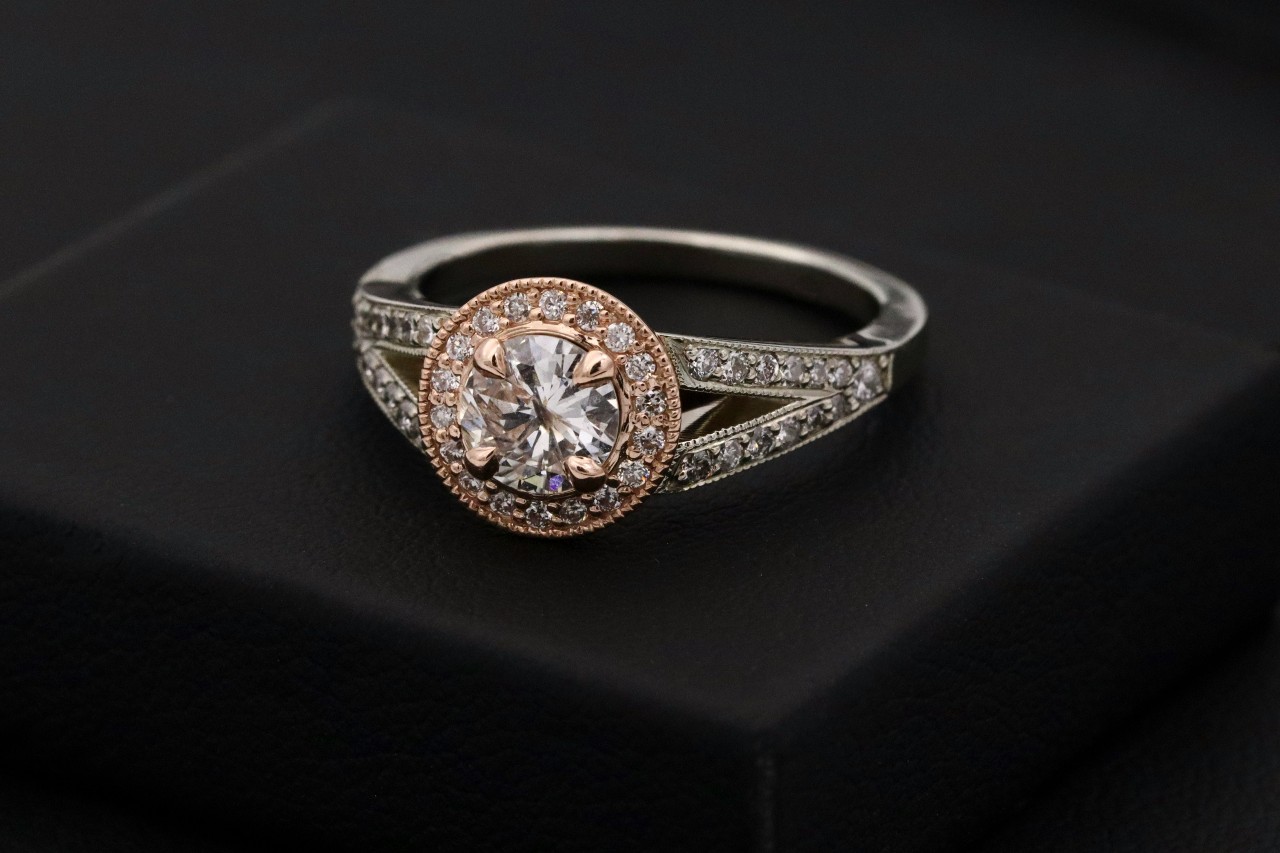 a vintage two-tone engagement ring sits on a black surface.