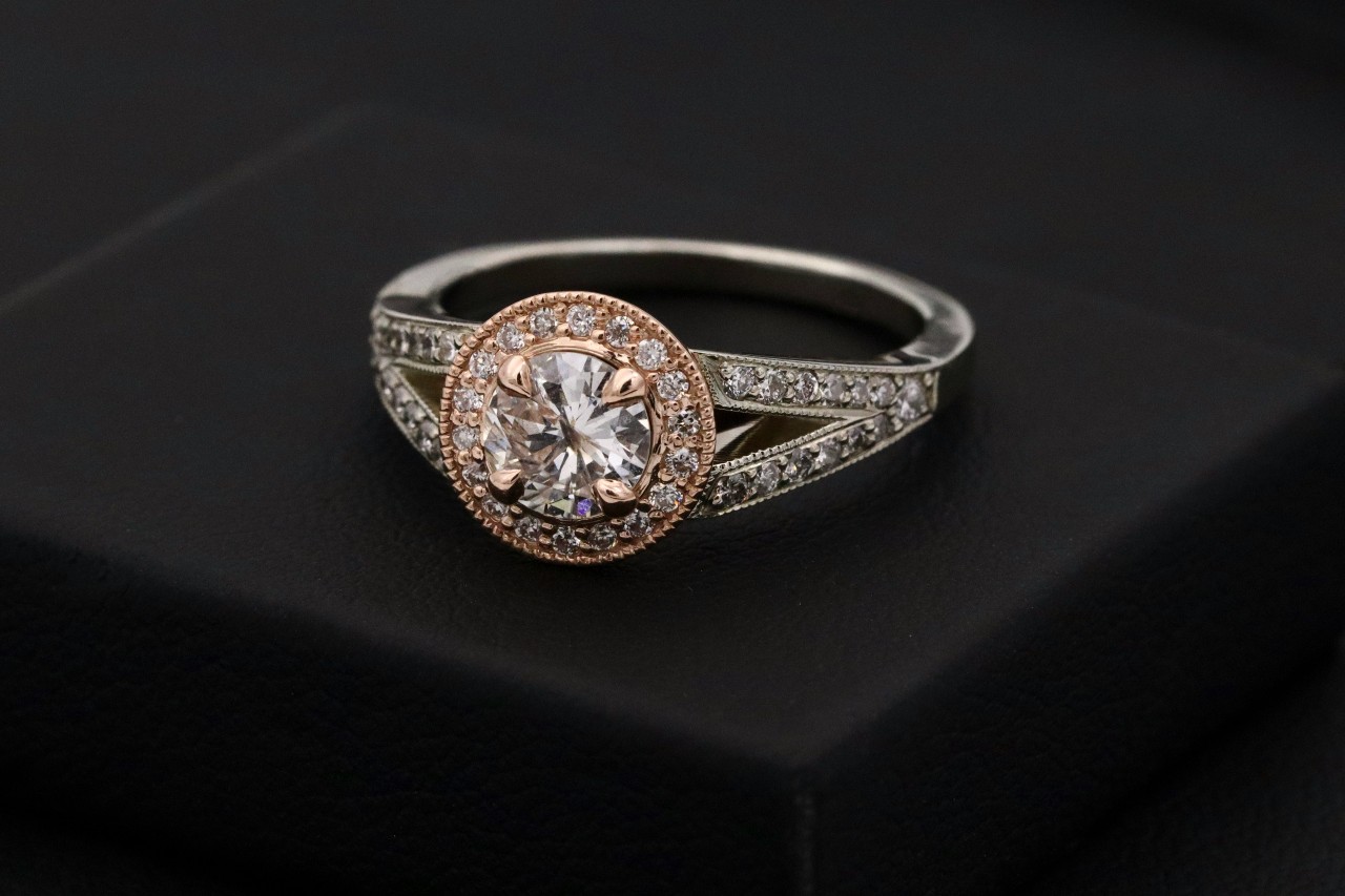 a vintage two-tone engagement ring sits on a black surface. a vintage two-tone engagement ring sits on a black surface.