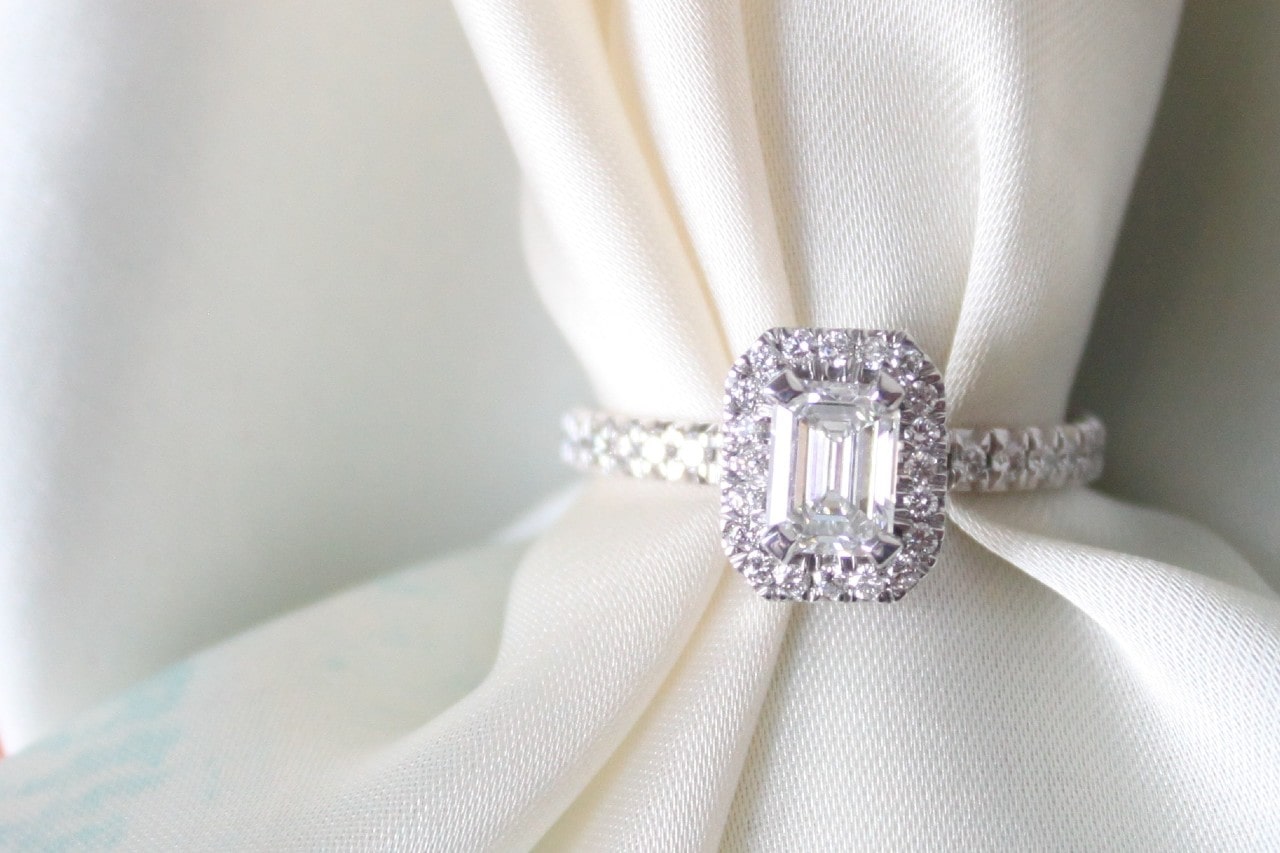 a white gold emerald cut halo engagement ring on a piece of white cloth