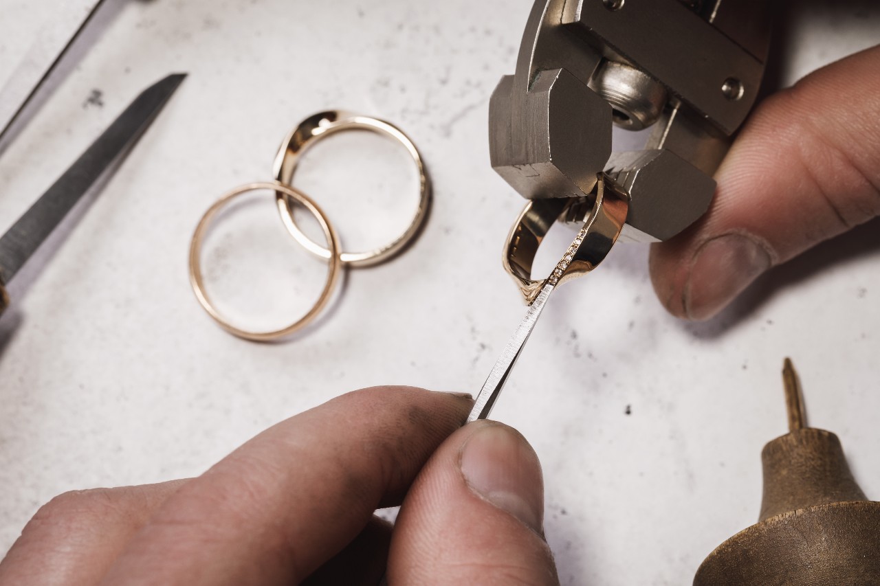 A close up of a jeweler working on a yellow gold wedding band. A close up of a jeweler working on a yellow gold wedding band.