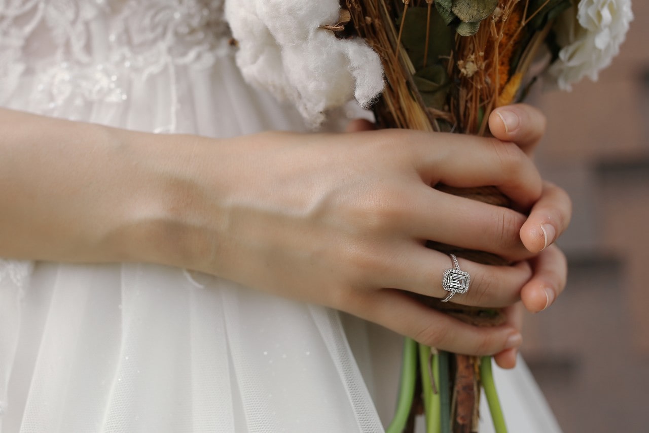 A close-up of a bride holding her bouquet and wearing a vintage-inspired engagement ring. A close-up of a bride holding her bouquet and wearing a vintage-inspired engagement ring.